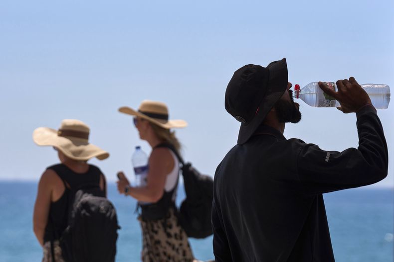 ARCHIVO - Un turista toma agua en un día de calor en la playa en Barcelona, el 2 de julio de 2025. (AP Foto/Emilio Morenatti, archivo)