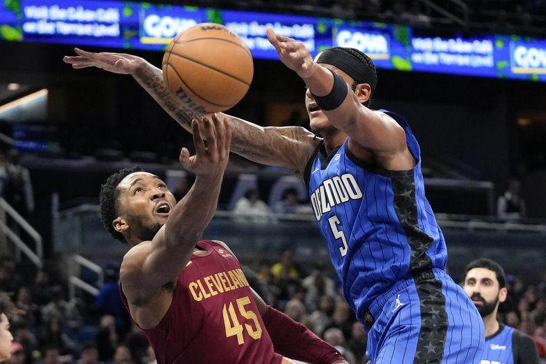 Donovan Mitchell (45), de los Cavaliers de Cleveland, dispara frente a Paolo Banchero (5), del Magic de Orlando, durante la primera mitad del juego de baloncesto de la NBA, el lunes 11 de diciembre de 2023, en Orlando, Florida. (AP Foto/John Raoux)