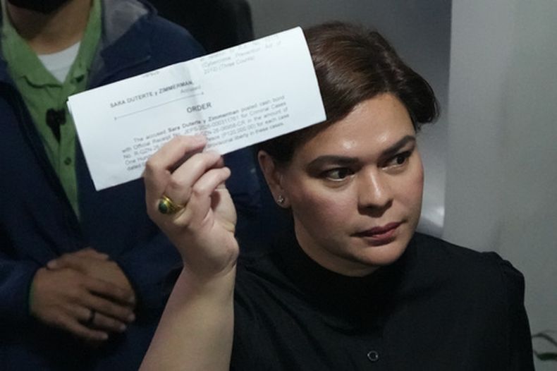 La vicepresidenta de Filipinas, Sara Duterte, muestra un documento a reporteros en la corte en Quenzón, el 5 de septiembre de 2026, tras la emisión de una orden de detención por supuestamente amenazar con matar al presidente y a otras dos personas. (AP Foto/Aaron Favila)