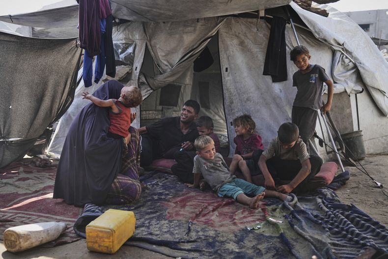 Abeer y Fadi Sobh, en su tienda junto a sus hijos, en un campamento para palestinos desplazados en la Franja de Gaza, el 24 de julio de 2025. (AP Foto/Jehad Alshrafi)