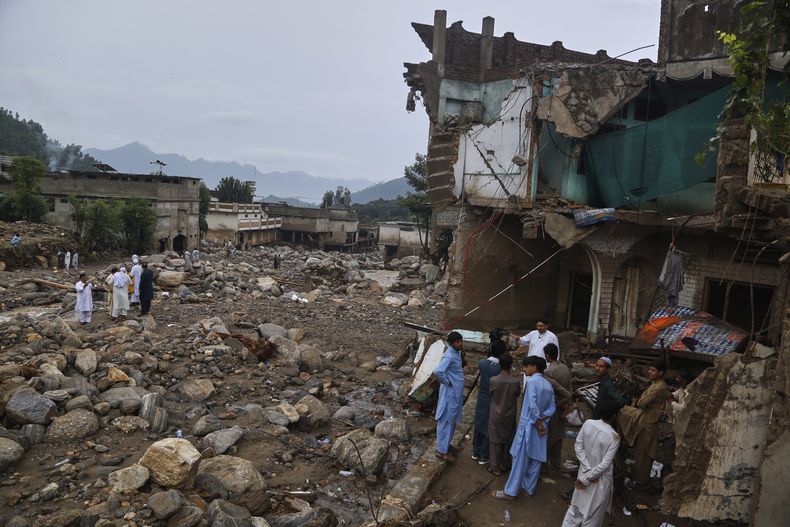 Gente observa casas y edificios dañados tras las inundaciones del viernes en la aldea de Pishoreen en el distrito de Buner, en el noroeste de Pakistán, el domingo 17 de agosto de 2025. (AP Foto/Muhammad Sajjad)