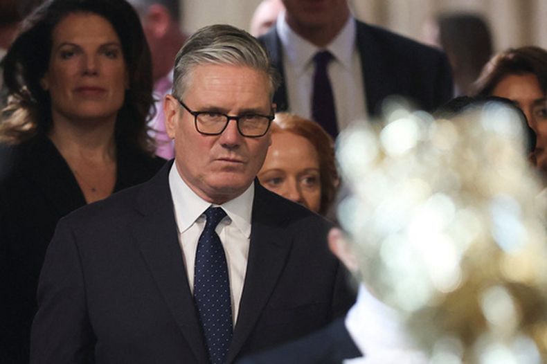 El primer ministro de Reino Unido, Keir Starmer (centro), camina por la Cámara de los Comunes para asistir al discurso de apertura del Parlamento, en el Palacio de Westminster, Londres, el 13 de mayo de 2026. (Toby Melville/Pool Foto vía AP)