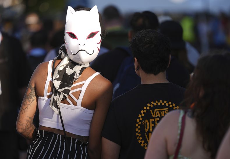 Una cosplayer usa su máscara al revés mientras espera en la fila con otros asistentes en la noche de vista previa internacional de la Comic-Con 2025 el miércoles 23 de julio de 2025 en San Diego. (Foto AP/Chris Pizzello)