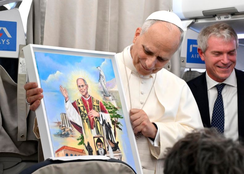 El papa León XIV muestra un regalo que recibió mientras habla con reporteros a bordo del avión que lo transportaba de regreso de una visita de seis días a Turquía y Líbano, el martes 2 de diciembre de 2025. (Alessandro Di Meo/Pool Foto vía AP)