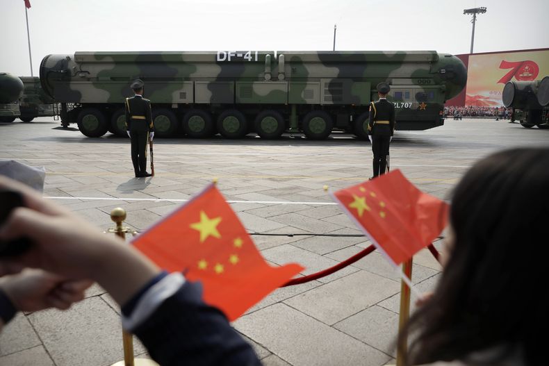 ARCHIVO - Espectadores ondean banderas chinas mientras vehículos militares con misiles balísticos desfilan en el 70mo aniversario de la fundación de la China comunista en Beijing, el 1 de octubre de 2019. (AP Foto/Mark Schiefelbein, Archivo)