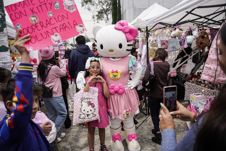 Una fan del personaje japonés Hello Kitty posa para una foto con una persona disfrazada de Hello Kitty en un mercado callejero en la Ciudad de México, el sábado 5 de octubre de 2024.(Foto AP/Aurea Del Rosario)