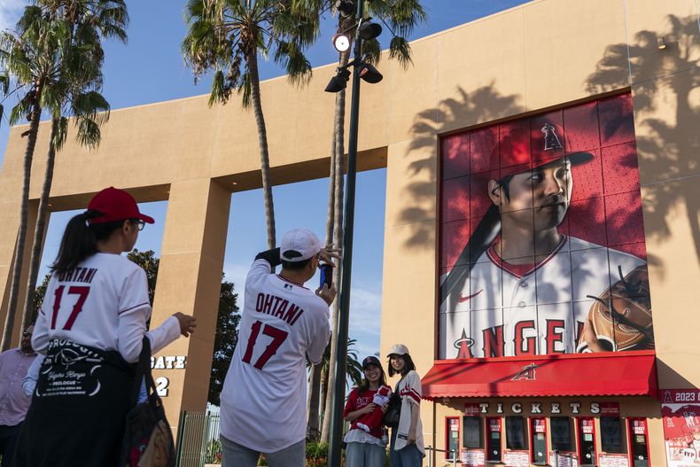 Aficionados toman fotos de una enorme imagen del astro de los Angelinos de Los Ángeles Shohei Ohtani antes del partido ante los Rangers de Texas, el miércoles 27 de septiembre de 2023, en Anaheim, California. (AP Foto/Jae C. Hong)