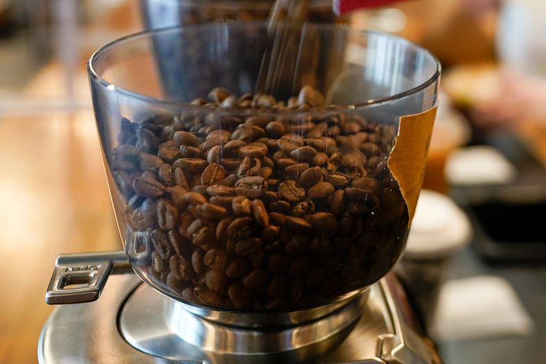Granos de café en un molinillo en una cafetería en College Park, Maryland, el 1 de septiembre de 2021. (AP Foto/Julio Cortez, Archivo)