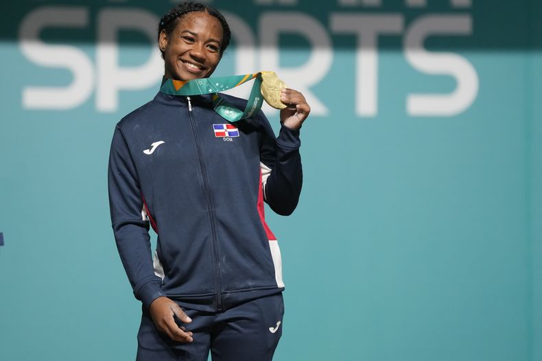 La dominicana Dahiana Ortiz muestra su medalla de oro en el podio de los 49 kilogramos del levantamiento de pesas en los Juegos Panamericanos en Santiago, Chile, el sábado 21 de octubre de 2023. (AP Foto/Moisés Castillo)