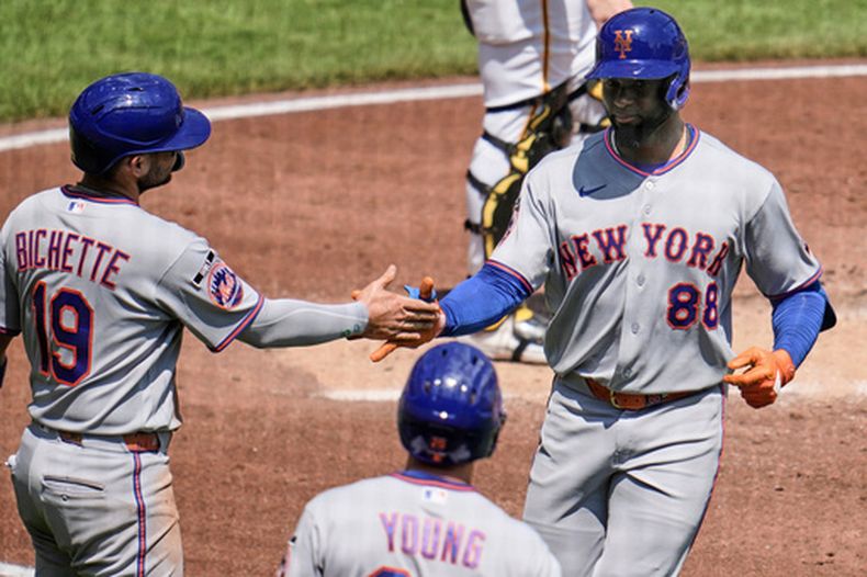 Luis Robert Jr. (88), de los Mets de Nueva York, es recibido en el plato por Bo Bichette (19) mientras se enfila al dugout después de batear un jonrón de dos carreras frente al lanzador de los Piratas de Pittsburgh, Jared Jones, durante la tercera entrada del juego de béisbol de Grandes Ligas, el domingo 9 de agosto de 2026, en Pittsburgh. (AP Foto/Gene J. Puskar)
