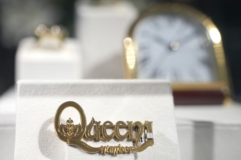 ARCHIVO- Uno de cuatro broches de oro exclusivos de Cartier con la leyenda Queen Number 1 creados en 1975 es exhibido en la casa de subastas Sothebys en Londres, el 3 de agosto de 2023. El broche fue un regalo del mánager de Queen para cada uno de sus integrantes después de que la canción “Bohemian Rhapsody” encabezó las listas de popularidad. Se vendió por 165.000 libras esterlinas (208.000 dólares) el 6 de septiembre de 2023. (Foto AP/Kirsty Wigglesworth, archivo)