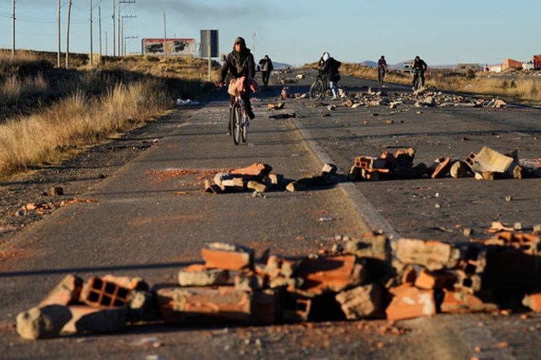 Varias personas rodean las barricadas levantadas por los manifestantes en la carretera que conecta La Paz con Oruro, cerca de El Alto, Bolivia, el sábado 16 de mayo de 2026. (AP Foto/Juan Karita)