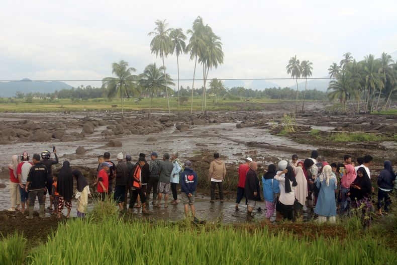 Gente inspeccionando una zona afectada por una inundación repentina que dejó varios muertos en Agam, Sumatra Occidental, Indonesia, el domingo 12 de mayo de 2024. Intensas lluvias y torrentes de lava fría y lodo que cayeron por las laderas de un volcán en la isla indonesia de Sumatra provocaron inundaciones repentinas que mataron a más de una docena de personas, según dijeron las autoridades el domingo. (AP Foto/Ali Nayaka)