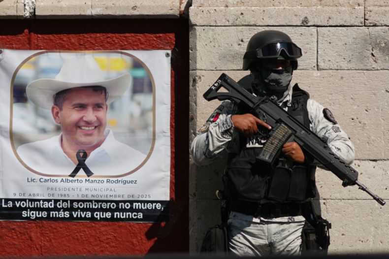 ARCHIVO - Un miembro de la Guardia Nacional se encuentra junto a un retrato del alcalde asesinado Carlos Manzo Rodríguez en Uruapan, México, el 21 de noviembre de 2025. (AP Foto/Eduardo Verdugo, Archivo)