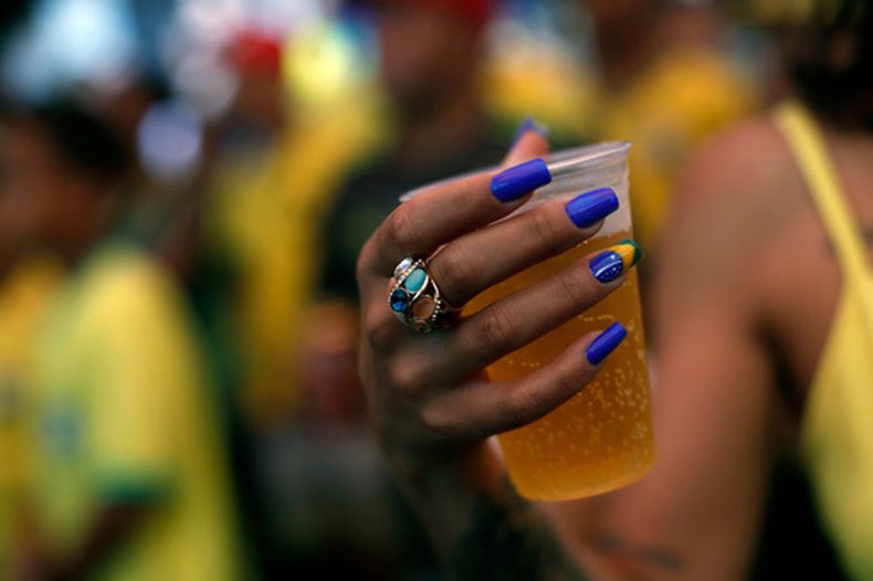 ARCHIVO - Una hincha del fútbol con sus uñas pintadas con la bandera de Brasil sostiene un vaso de cerveza durante el partido contra Serbia en el Mundial 2022, el 24 de noviembre de 2022, en Río de Janeiro. (AP Foto/Bruna Prado)