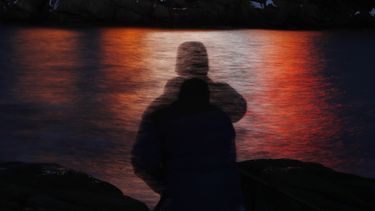 ARCHIVO - En esta foto, tomada con un tiempo de exposición largo, la silueta de un hombre aparece frente a las luces reflejadas en las aguas de Cape Neddick en Maine , el 11 de diciembre de 2017. (AP Foto/Robert F. Bukaty, Archivo)