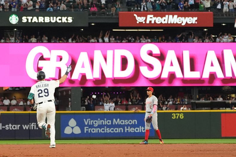 Cal Raleigh (29), de los Marineros de Seattle, recorre las bases después de batear un grand slam mientras Edwin Arroyo (2), segunda base de los Rojos de Cincinnati, observa durante la séptima entrada del juego de béisbol de Grandes Ligs, del lunes 20 de julio de 2026, en Seattle. (AP Foto/Lindsey Wasson)