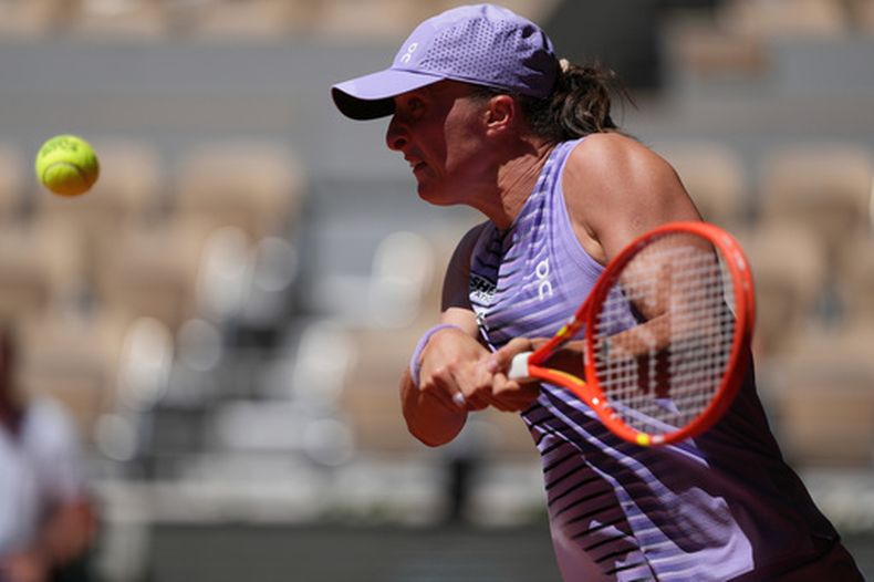 Iga Swiatek, de Polonia, devuelve el balón a Sara Bejlek, de la República Checa, durante su partido de segunda ronda de individuales femeninos en el torneo de tenis de Roland Garros en París, el miércoles 27 de mayo de 2026. (Foto AP/Thibault Camus)
