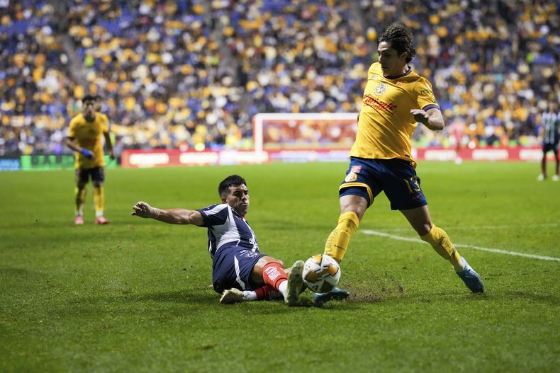 Jorge Rodríguez, del Monterrey, se desliza en busca de despojar del balón a Alan Cervantes, del América, en la ida de la final de la Liga MX, el jueves 12 de diciembre de 2024, en Puebla (AP Foto/Eduardo Verdugo)