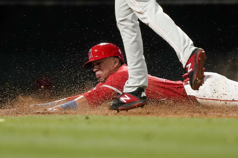 Ehire Adrianza (abajo), de los Angelinos de Los Ángeles, se arrastra sobre el campo junto al relevista de los Filis de Filadelfia Seranthony Dominguez para anotar en un wild pitch en el séptimo inning del juego de la MLB que enfrentó a ambos equipos, el 29 de abril de 2024, en Anaheim, California. (AP Foto/Ryan Sun)