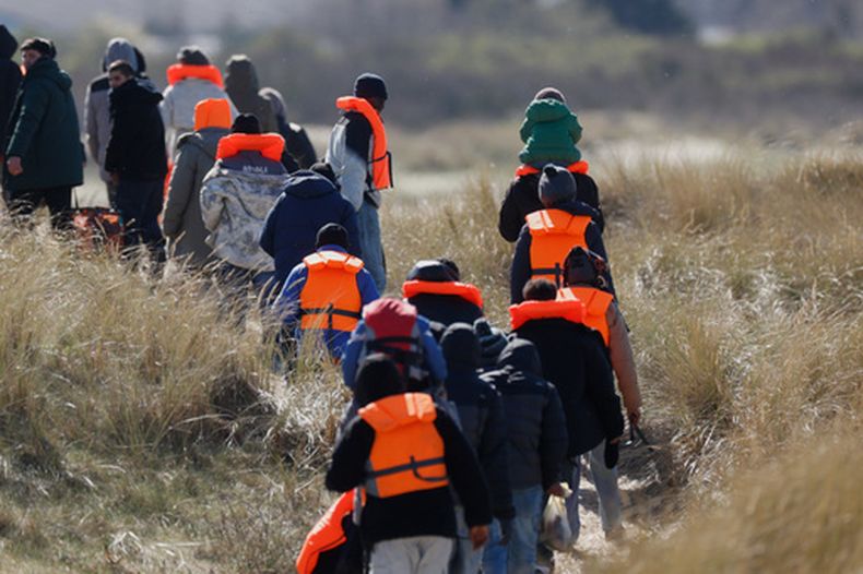 Migrantes que tratan de llegar a Reino Unido, caminan por una playa en Gravelines, en el norte de Francia, el 18 de marzo de 2026. (AP Foto/Jean-François Badias)