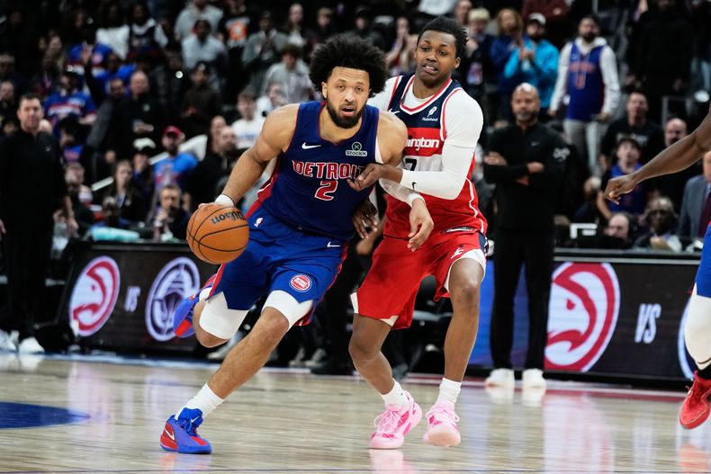 Cade Cunningham, izquierda, de los Pistons de Detroit, lleva el balón hacia la canasta superando la marca defensiva de Bub Carrington, de los Wizards de Washington, durante el tiempo extra del partido de baloncesto de la NBA, el lunes 10 de noviembre de 2025, en Detroit. (AP Foto/Ryan Sun)