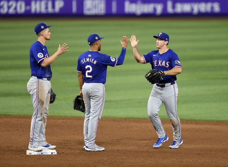 El campocorto de los Rangers de Texas Corey Seager celebra con sus compañeros Marcus Semien y Wyatt Langford el triunfo ante los Marlins de Miami el sábado 1 de junio del 2024. (AP Foto/Michael Laughlin)