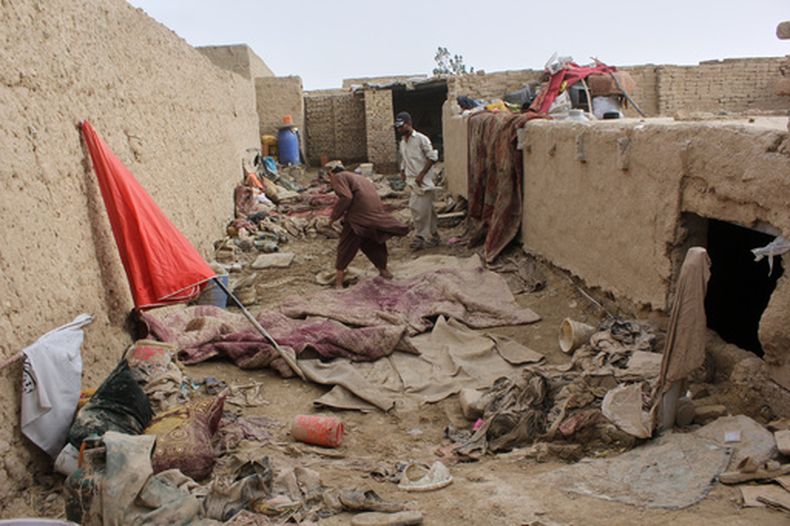 Vecinos inspeccionan una casa dañada tras inundaciones, aludes y tormentas en la provincia de Kandahar, Afganistán, el domingo 29 de marzo de 2026. (AP Foto/Sibghatullah)
