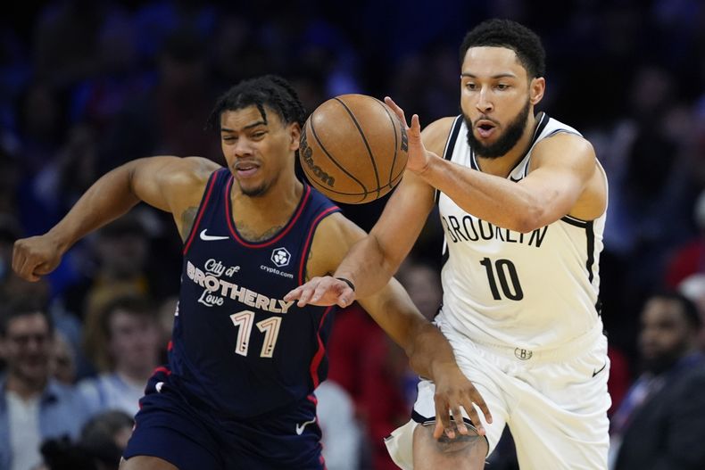 Ben Simmons, de los Nets de Brooklyn, a la derecha, y Jaden Springer, de los 76ers de Filadelfia, persiguen un balón suelto durante la segunda mitad de un partido de baloncesto de la NBA, el sábado 3 de febrero de 2024, en Filadelfia. (AP Foto/Matt Slocum)