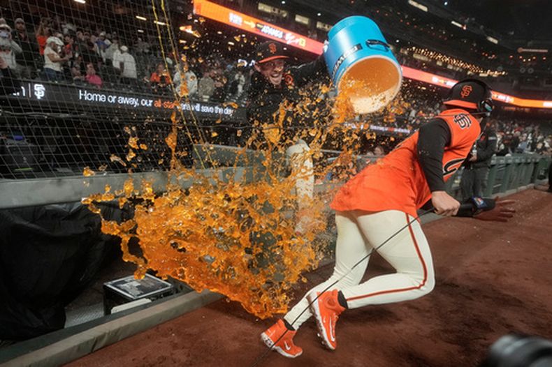 El dominicano Willy Adames, de los Gigantes de San Francisco, corre para evitar que su compañero Trent Harris lo empape con la hielera, tras la victoria sobre los Tigres de Detroit, el viernes 7 de agosto de 2026 (AP Foto/Jeff Chiu)