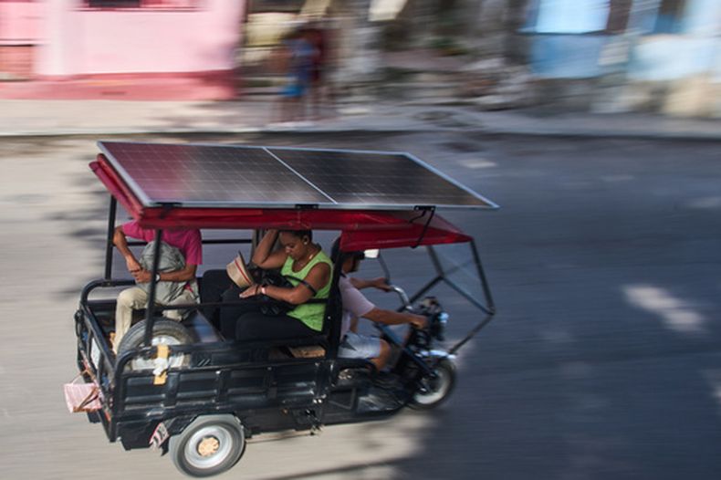 Varias personas viajan en un triciclo eléctrico equipado con un panel solar en La Habana, Cuba, el viernes 10 de julio de 2026. (AP Foto/Ramón Espinosa)