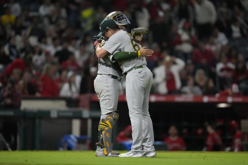 Shea Langeliers y el relevista Trevor May, de los Atléticos de Oakland, festejan la victoria sobre los Angelinos de Los Ángeles, el sábado 30 de septiembre de 2023 (AP Foto/Ashley Landis)
