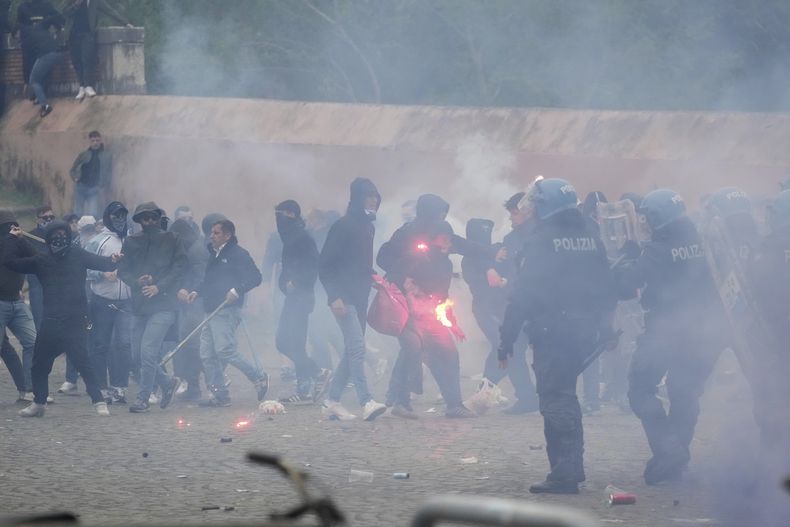 Hinchas de la Lazio se enfrentan con policías italianos con equipo antidisturbios fuera del estadio olímpico antes del inicio del partido de fútbol italiano entre la Lazio y la Roma en Roma, el domingo 13 de abril de 2025. (AP Foto/Gregorio Borgia)