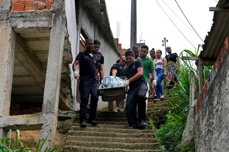 Trabajadores forenses cargan el cuerpo de una persona asesinada durante enfrentamientos entre pandillas rivales, mientras la familia del fallecido camina detrás, en el vecindario de Jardim Esperanca a las afueras of Salvador, en el estado Bahia, Brasil, el viernes 28 de agosto de 2026. (AP Foto/Eraldo Peres)