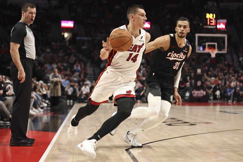 El escolta del Heat de Miami Tyler Herro (14) lleva el balón mientras el alero de los Trail Blazers de Portland, Toumani Camara (33), defiende durante la primera mitad, el sábado 11 de enero de 2025, en Portland, Oregon (AP Foto/Amanda Loman)