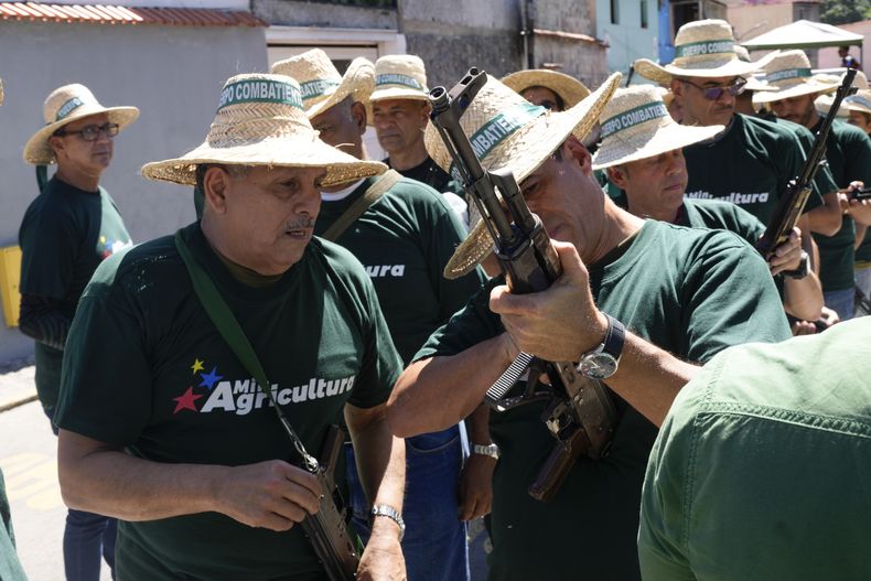 Trabajadores públicos sostienen rifles antes de una marcha de milicias respaldadas por el gobierno en Caracas, Venezuela, el martes 7 de enero de 2025, días antes de la toma de posesión del presidente Nicolás Maduro para un tercer mandato. (AP Foto/Matías Delacroix)