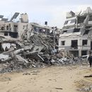 Palestinos caminan junto a un edificio destruido en el bombardeo israelí de la Franja de Gaza, en Ciudad de Gaza, el miércoles 3 de enero de 2024. (AP Foto/Mohammed Hajjar)