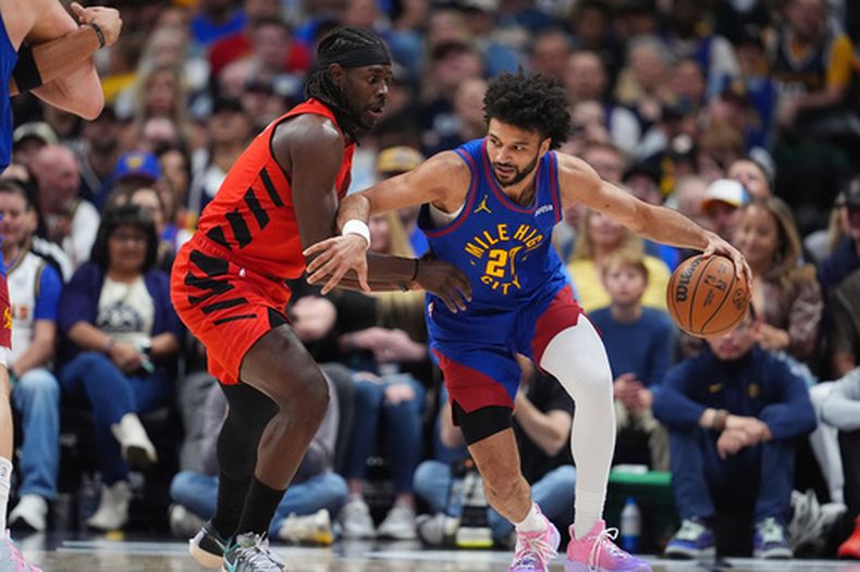 Jamal Murray, derecha, de los Nuggets de Denver, lleva el balón e intenta pasar de Jrue Holiday, izquierda, de los Trail Blazers de Portland, en la primera mitad del juego de baloncesto de la NBA, el domingo 22 de marzo de 2026, en Denver. (AP Foto/David Zalubowski)