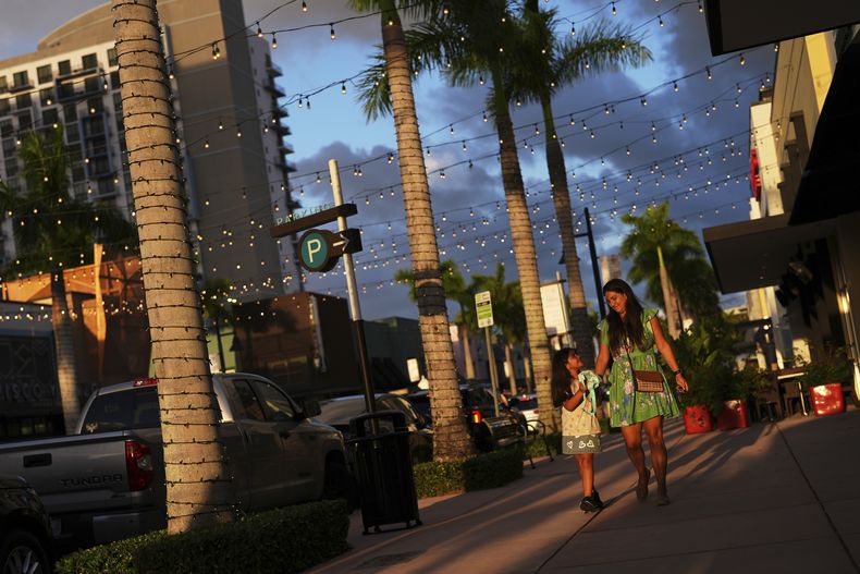 Una mujer y una niña caminan por una calle comercial, en Doral, Florida, el sábado 5 de abril de 2025. (AP Foto/Rebecca Blackwell)