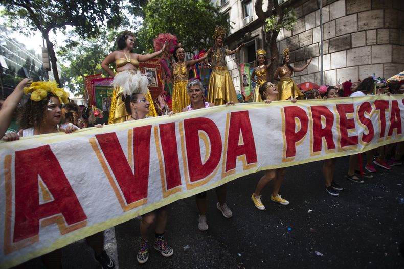 Juerguistas sostienen una pancarta que dice en portugués; La vida vale la pena, en homenaje a la actriz brasileña Fernanda Torres, que compite por el Oscar a la mejor actriz por su papel en “Ainda estou aquí”, en una fiesta callejera de precarnaval Cordao do Boitata en Río de Janeiro, el domingo 23 de febrero de 2025. (Foto AP/Bruna Prado)