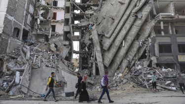 ARCHIVO - Palestinos caminan frente a edificios impactados por ataques israelíes en Ciudad de Gaza, el viernes 24 de noviembre de 2023. (AP Foto/Mohammed Hajjar)