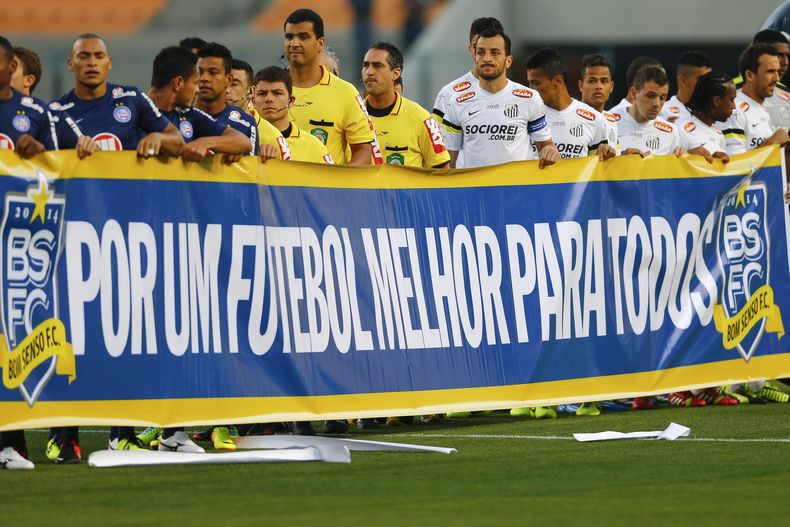En esta fotograf&iacute;a del 14 de noviembre de 2013, jugadores de los equipos de f&uacute;tbol Santos y Bah&iacute;a sostienen una pancarta que dice "Por un mejor f&uacute;tbol para todos" durante un encuentro del campeonato brasile&ntilde;o e