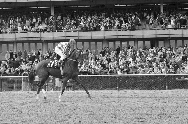 ARCHIVO - Foto del 6 de noviembre de 1973, el campeón Secretariat con el jinete Ron Turcotte pasa junto a las gradas del Aqueduct Rack Track en Nueva York en su última aparición. (AP Foto/Dave Pickoff, Archivo)