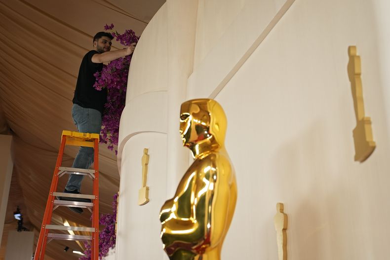 Un trabajador prepara la alfombra roja junto a una estatua de los Oscar previo a la 96a entrega de los Premios de la Academia el sábado 9 de marzo de 2024, en Los Angeles. (Foto AP/John Locher)