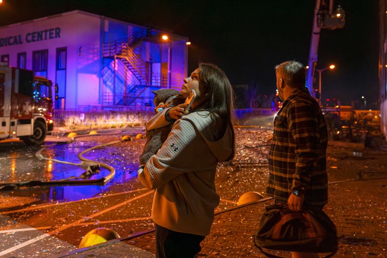 Personas observan cómo socorristas trabajan para extinguir un incendio tras un ataque ruso en Kiev, Ucrania, el martes 25 de noviembre de 2025. (AP Foto/Dan Bashakov)