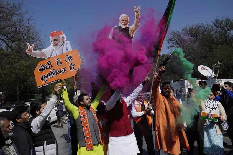 Simpatizantes del partido Bharatiya Janata Party, con carteles con la imagen del primer ministro de India, Narendra Modi, celebran la ventaja de la formación en el conteo de las elecciones estatales en Delhi, en Nueva Delhi,India, el 8 de febrero de 2025. (AP Foto/Manish Swarup)