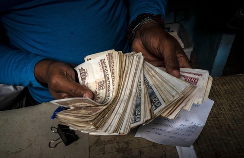 ARCHIVO - Un trabajador muestra un fajo de pesos cubanos el 11 de diciembre de 2020, en La Habana, Cuba. (AP Foto/Ramón Espinosa, Archivo)