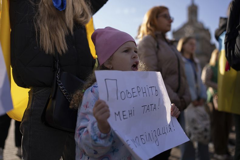 Liliia, que espera que su padre regrese del frente, sostiene un cartel que dice Traigan a mi padre de vuelta. ¡Desmovilización!, durante una protesta de familias de militares ucranianos en la Plaza de la Independencia en Kiev, Ucrania, el viernes 27 de octubre de 2023. (Foto AP/Alex Babenko)