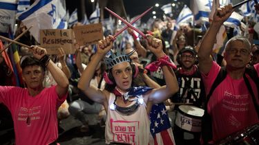 Una manifestante porta una corona como la de Estatua de la Libertad y una bandera estadounidense durante una protesta contra los planes del primer ministro israelí Benjamin Netanyahu para reformar el sistema judicial de la nación, frente a la oficina de la embajada de Estados Unidos en Tel Aviv, el jueves 13 de julio de 2023. (AP Foto/Maya Alleruzzo)
