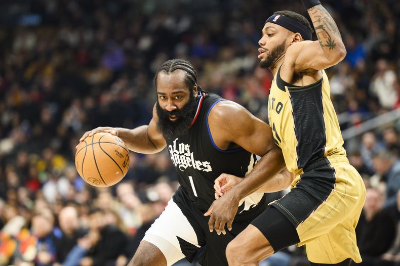 James Harden, base de los Clippers de Los Ángeles, conduce el balón frente a Bruce Brown, de los Raptors de Toronto, el viernes 26 de enero de 2024 (Christopher Katsarov/The Canadian Press via AP)